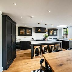 a kitchen with black cabinets and counter tops next to a dining room table in front of an island