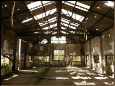 an abandoned building with lots of windows and plants in the center, surrounded by brick walls