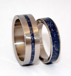 two wedding bands with black and white marble inlays on each side, set against a plain background