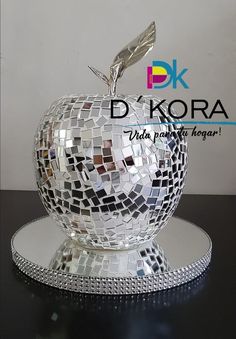 an apple made out of mirrored tiles sitting on top of a black table with the words d kora above it