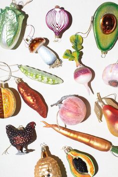 an assortment of fruit and vegetable ornaments on a white surface