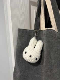 a gray bag with a white crocheted bunny keychain hanging from it