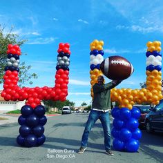 a man holding a football in front of balloons spelling out the word'joy '