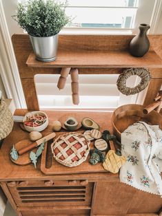 a wooden table topped with pots and pans next to a potted plant on top of a window sill