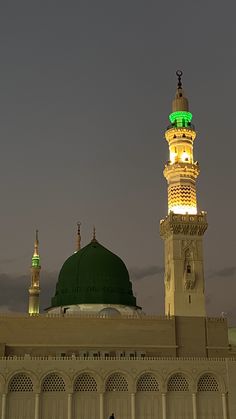 a large white building with a green dome and lights on it's side at night