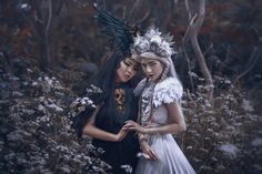 two women dressed in white and black standing next to each other with flowers on their head