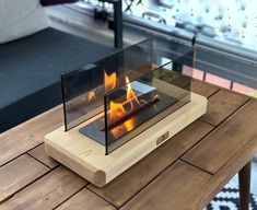 a glass fire pit sitting on top of a wooden table