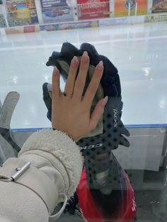 a person's hand on top of a pair of gloves in front of an ice rink