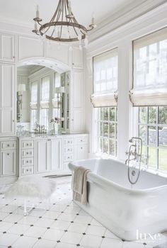 a white bathroom with a claw foot tub and chandelier