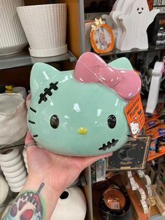 a person holding up a hello kitty piggy bank