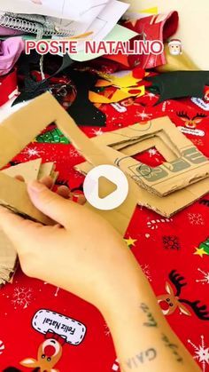 someone cutting out christmas cards with scissors on a red tablecloth covered in wrapping paper