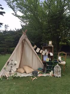 a teepee sitting on top of a lush green field next to a wooden shelf