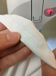 a person is sewing on a piece of white cloth with a needle in their left hand