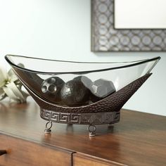 a glass bowl filled with black balls on top of a wooden dresser