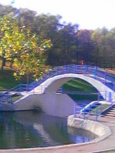 a white bridge over a body of water with trees and bushes in the back ground