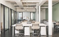 an empty office with chairs and desks in the middle of it, surrounded by glass doors