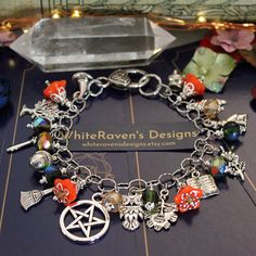 a bracelet with various charms on it and a crystal box in the background that says white raven's designs