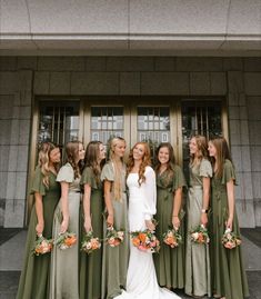 a group of women standing next to each other in front of a door wearing green dresses