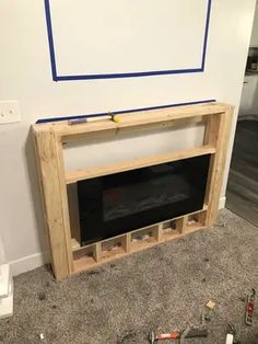 an unfinished fireplace is shown with tools on the floor next to it and a whiteboard behind it