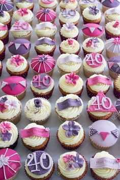 cupcakes decorated with pink, purple and white icing are arranged in rows