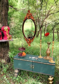 an old trunk is sitting in the grass near a mirror and other items that are on display