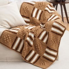 a brown and white afghan sitting on top of a couch