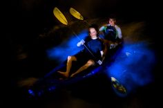 two people are in a boat with paddles on the water at night and one person is smiling