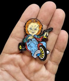 a hand holding a small cartoon character pin