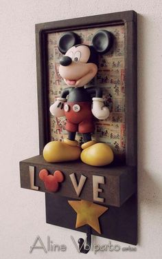 a mickey mouse figurine sitting on top of a shelf with the word love