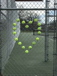 several tennis balls are hanging from a chain link fence