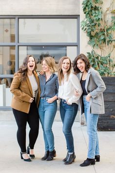 four women standing together in front of a building