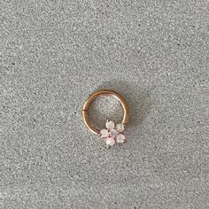 a gold ring with three small pink flowers on the outside, sitting on a gray surface