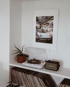 a record player sitting on top of a white shelf next to a potted plant