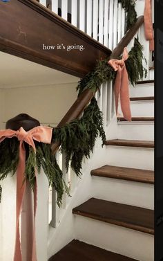 the garland on the stairs has been tied with pink ribbon and is ready to go down