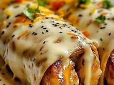 two enchiladas covered in cheese and sauce on a plate with other food items