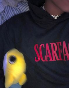 a close up of a person wearing a black shirt with a yellow bird on it