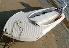 a white boat sitting on top of a sandy beach next to the ocean with a rope