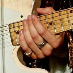 a close up of a person playing an electric guitar with their hands on the strings