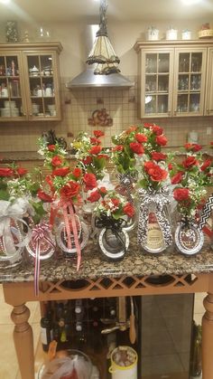 many vases filled with red flowers on a kitchen counter