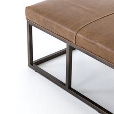 a brown leather bench sitting on top of a white floor