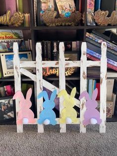 three wooden easter bunnies sitting in front of a book shelf with books on it