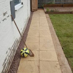 a yellow and black soccer ball laying on the ground next to a white brick wall