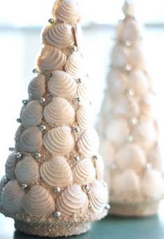 two small christmas trees made out of seashells on a table next to each other