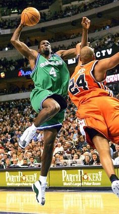 two basketball players in the air during a game with an audience watching from the stands