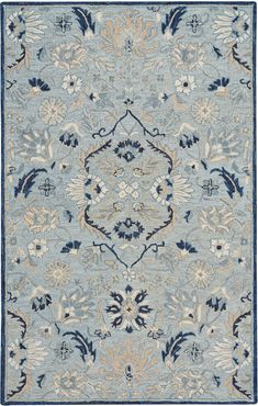 a blue and beige rug with an ornate design on the center, surrounded by flowers