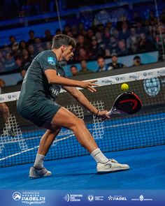 a man hitting a tennis ball with a racquet on a blue tennis court