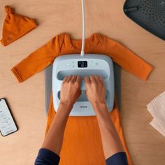 a person working on an electronic device with other items around it and in the background