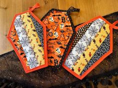 three halloween bibs are sitting on top of a lace doily with skulls and spider webs