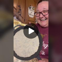 a woman is smiling while holding a pan with food in it on the stove top