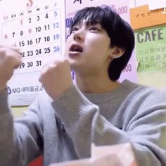 a young man eating food in front of a wall with calendars on the walls